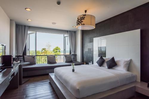 a bedroom with a large bed and a large window at Cher Resort SHA Plus Certified in Cha Am