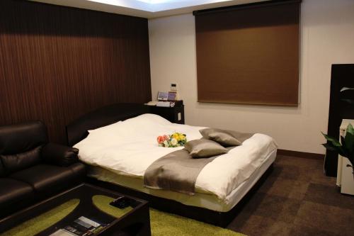 a room with a bed with a couch and a table at Hotel Pal Anesso Nakatsu (Love Hotel) in Nakatsu