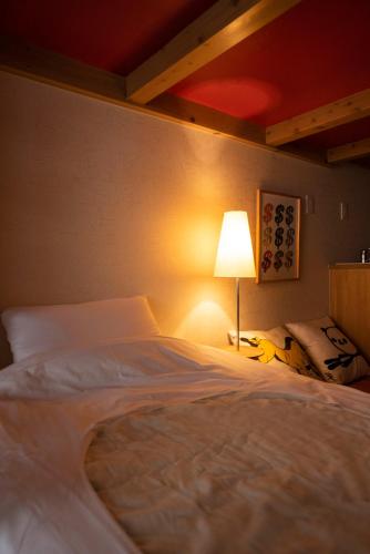 a bedroom with a large white bed with a lamp at BEYOND HOTEL Takayama 2nd in Takayama