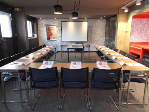 a conference room with tables and chairs and a screen at ibis Valence Sud in Valence