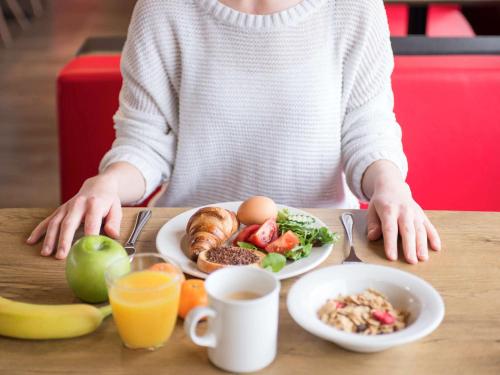 a person sitting at a table with a plate of food at Ibis Schiphol Amsterdam Airport in Badhoevedorp