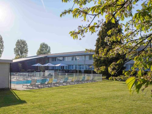 a building with chairs and a lawn in front of it at Novotel Lille Aéroport in Lesquin