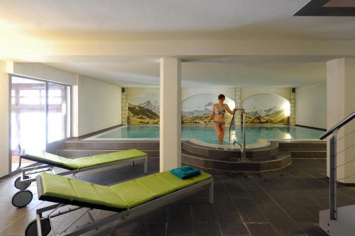 a man is standing in a swimming pool at Hotel Krone Budget in Lenk