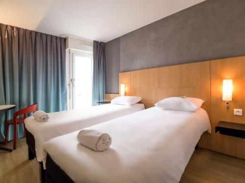 una camera d'albergo con due letti e una finestra di ibis Rennes Beaulieu a Cesson-Sévigné