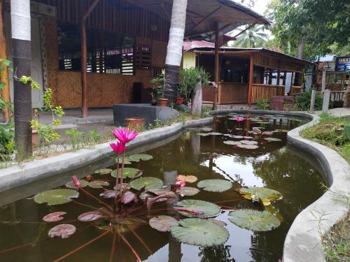 a pond with a pink flower in front of a building at Havelock Farms Resort in Havelock Island