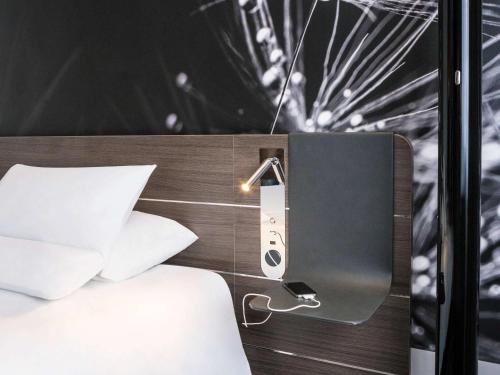a hotel room with a bed with a sign next to it at Novotel Saclay in Saclay