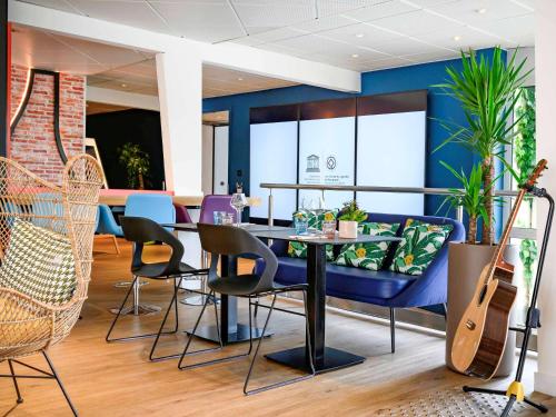 a dining room with a table and chairs and a guitar at Novotel Dijon Sud in Marsannay-la-Côte