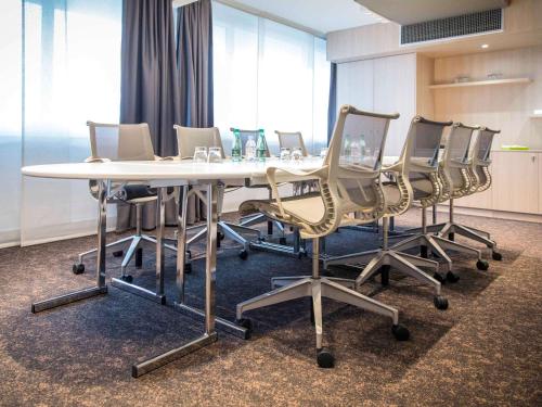 a conference room with a white table and chairs at Novotel Lille Aéroport in Lesquin
