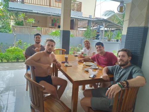 Un gruppo di uomini seduti intorno a un tavolo di Dwiki Putra Home Stay a Nusa Lembongan