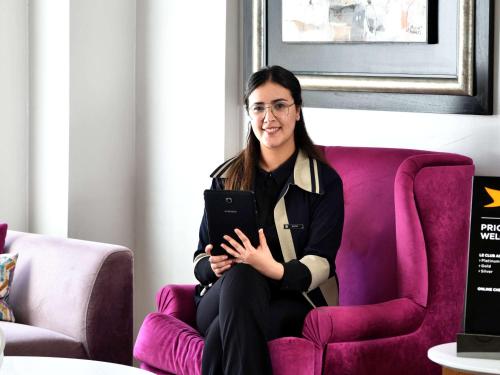 a woman sitting on a purple chair with a tablet at Pullman Mazagan Royal Golf & Spa in El Jadida