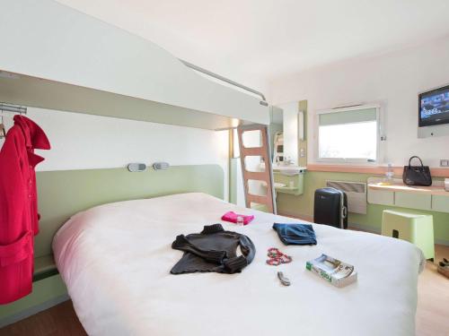 a bedroom with a bed with a backpack and clothes at ibis budget Poitiers Sud in Poitiers