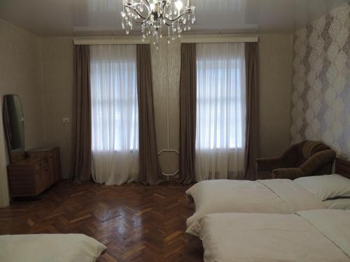 a bedroom with two beds and a chandelier and two windows at Blue Guesthouse in Stepantsminda