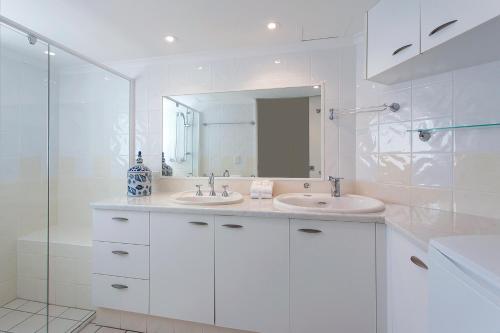 a white bathroom with two sinks and a mirror at Noosa Shores Resort in Noosa Heads