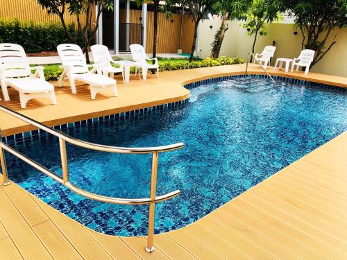 a swimming pool with white chairs and a pool at Ingnaam Hotel in Ban Talat Rangsit