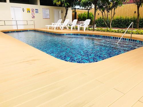 a swimming pool with a wooden floor and white chairs at Ingnaam Hotel in Ban Talat Rangsit