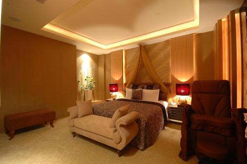 a hotel room with a bed and a chair at MUDU BREEZE MOTEL in Shulin