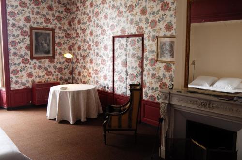 a room with a table and a bed and a fireplace at Château de Villemorien in Villemorien