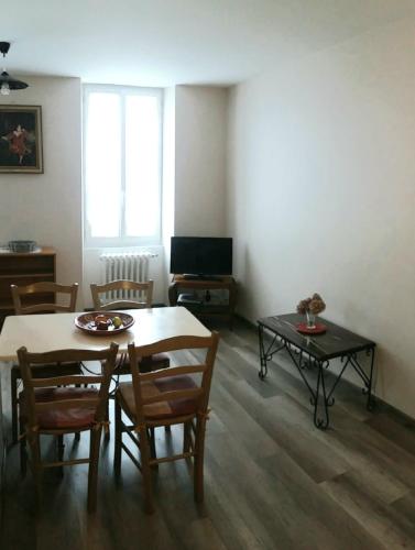 ein Wohnzimmer mit einem Tisch, Stühlen und einem TV in der Unterkunft Rubis in Jonzac
