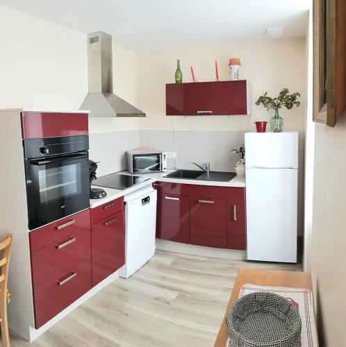 a kitchen with red cabinets and a white refrigerator at Rubis in Jonzac