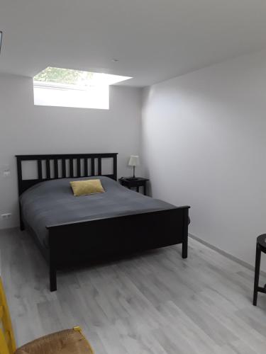 ein Schlafzimmer mit einem schwarzen Bett in einem weißen Zimmer in der Unterkunft Le Gîte Dameryat in Damery