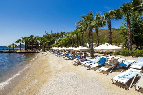 un gruppo di sedie e ombrelloni su una spiaggia di Fortezza Beach Resort a Hisarönü