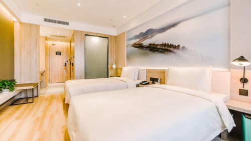 two beds in a hotel room with a painting on the wall at Atour Hotel Wuhan Changqing Road Branch in Wuhan