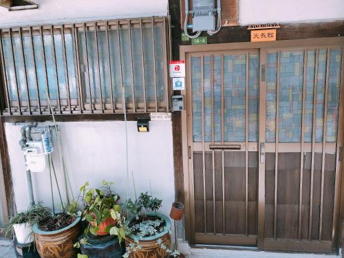 a door of a building with potted plants in front of it at Ryokoheya Tenchokan in Osaka