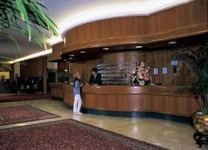 a woman standing at a bar in a lobby at Hotel Terme Marconi in Montegrotto Terme