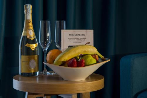 a bowl of fruit on a table with a bottle of champagne at Hotel Admiral in Budva
