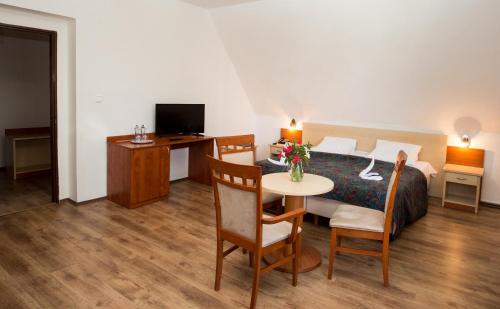 a hotel room with a bed and a table and a desk at Fontána Lipno in Černá v Pošumaví
