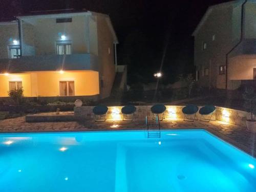 a swimming pool in front of a house at night at Caretta Village in Toroni