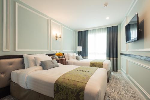 バンコクにあるSara's Hotelのベッド2台とテレビが備わるホテルルームです。