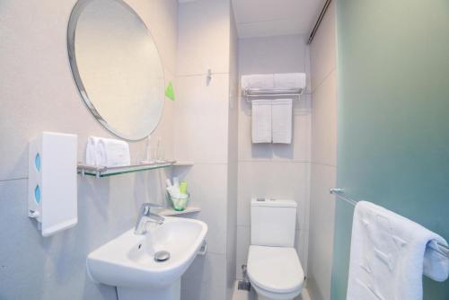 a bathroom with a sink and a toilet and a mirror at Hotel Ease Mong Kok in Hong Kong