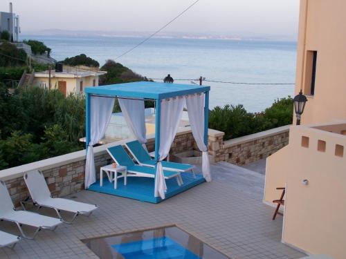 a gazebo and chairs on a patio overlooking the ocean at Sea Breeze Apartments Chios in Monolia
