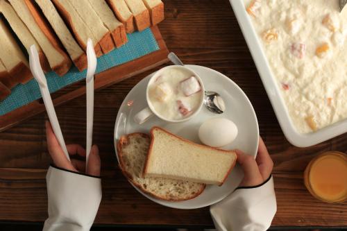 a person holding a plate of food with a egg and a sandwich at UNPLAN Shinjuku in Tokyo