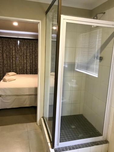 a shower with a glass door in a bedroom at Windmill Farm in Bergville