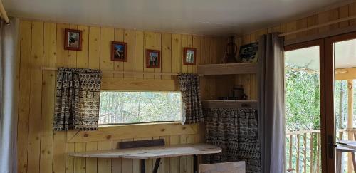 um quarto com paredes de madeira, uma janela e uma mesa em LA CABANE PERCHEE em Villelaure