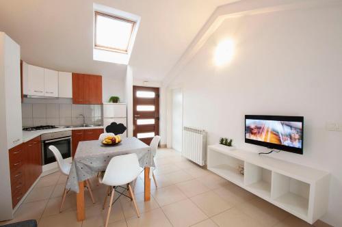 a kitchen with a table and a tv on a wall at Apartment Dva Oriha in Funtana