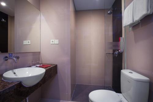 y baño con aseo blanco y lavamanos. en favehotel Hasyim Ashari Tangerang en Tangerang