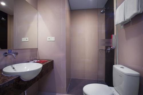 een badkamer met een wit toilet en een wastafel bij favehotel Hasyim Ashari Tangerang in Tangerang
