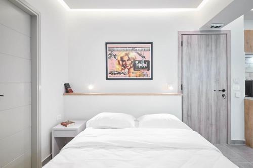 a white bedroom with a bed and a poster on the wall at Stay in a hip decorated studio near Acropolis! in Athens