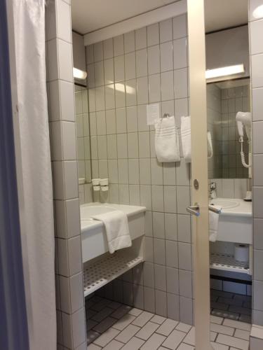 a bathroom with a tub and a sink and a mirror at City Hotel Nattergalen in Odense
