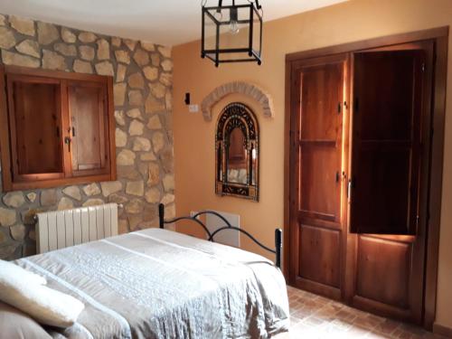 1 dormitorio con cama y pared de piedra en Casita Vista Alegre, en Castril