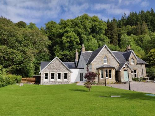 a white house with a blue roof and green grass at Rokeby Manor in Invergarry