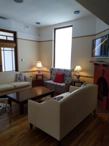 a living room with white couches and a coffee table at Savoy Hotel Beaufort-West in Beaufort West