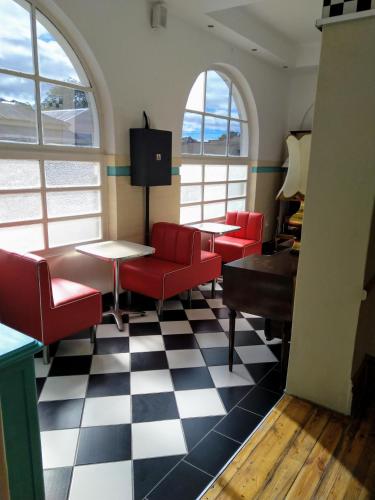 a restaurant with red chairs and tables and a piano at Savoy Hotel Beaufort-West in Beaufort West