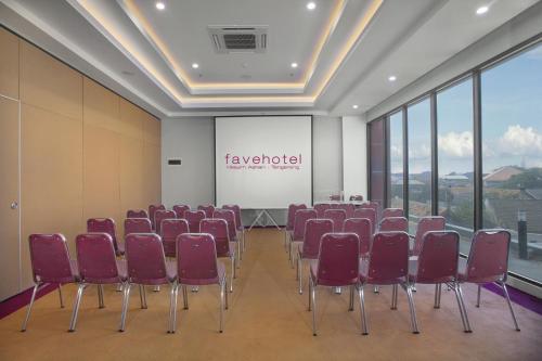 a conference room with red chairs and a screen at favehotel Hasyim Ashari Tangerang in Tangerang