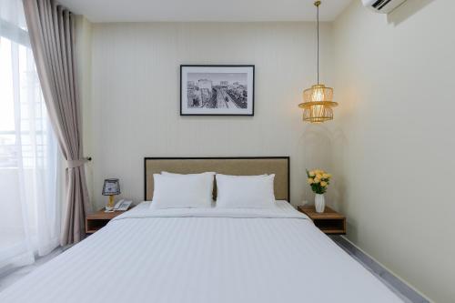 sypialnia z dużym białym łóżkiem z białymi poduszkami w obiekcie The Akoya Saigon Hotel w Ho Chi Minh