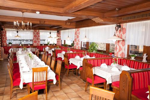 a dining room with white tables and red chairs at Hotel Neuwirt in Finkenberg