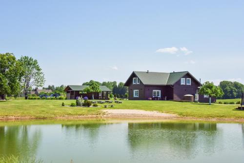 a house with a pond in front of it at Sodyba Puodžių Kaimas in Mackėnai